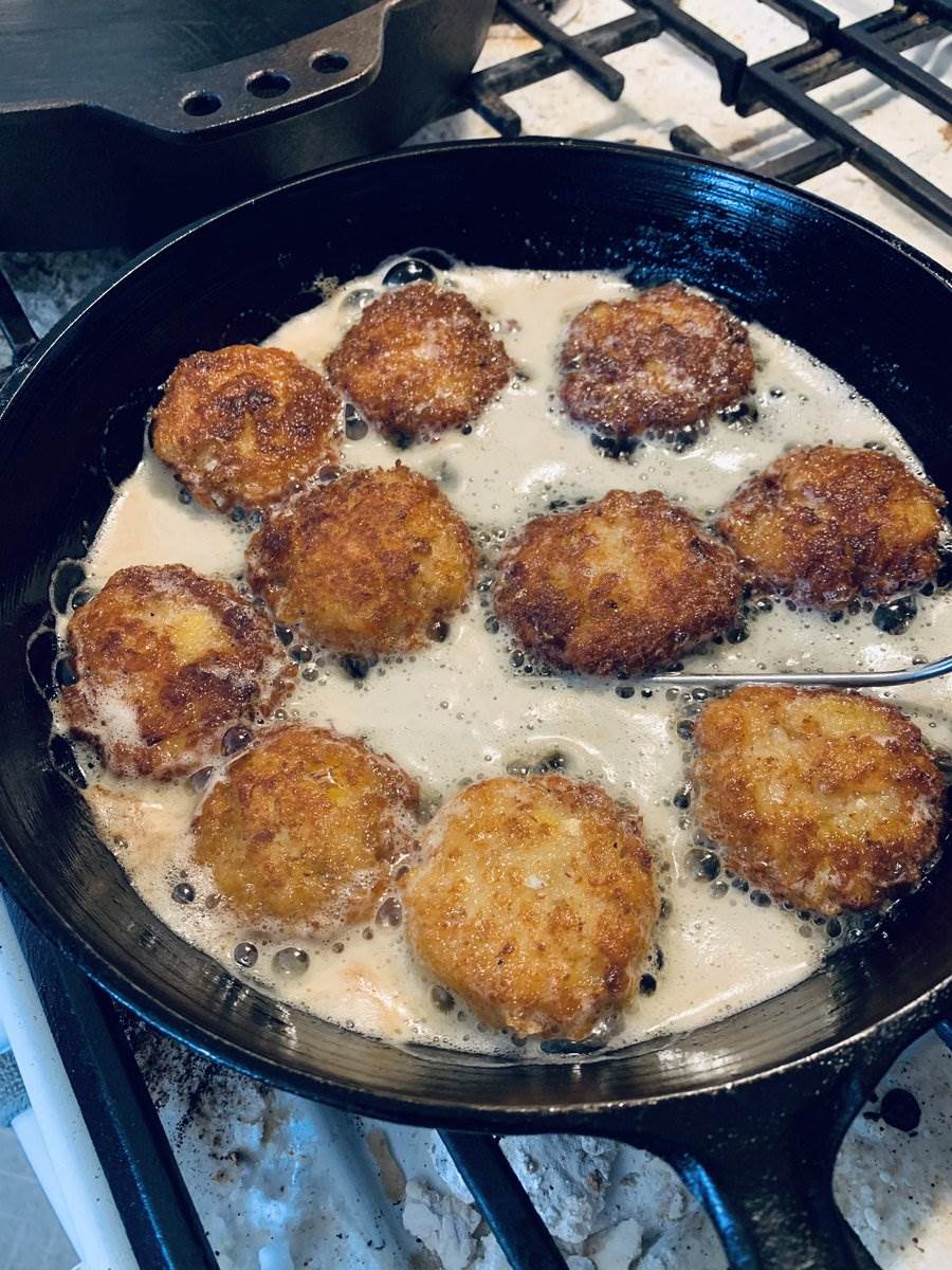 Fish cakes frying in butter in a cast-iron pan, 2025 — photograph by Ray Patrick