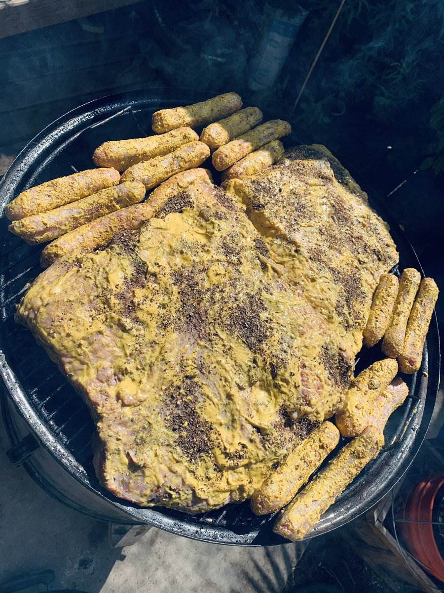 Mustard-slathered brisket and sausages on the smoker, 2024 — photograph by Ray Patrick
